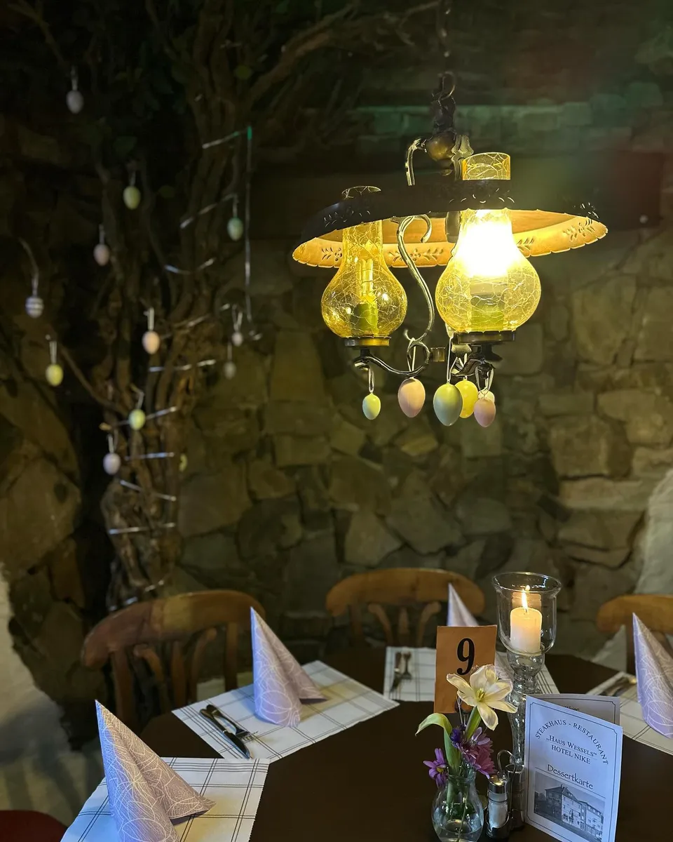 Gaststube mit Natursteinwand, Kerzenlicht und eingedecktem Tisch im Steakhaus Haus Wessels