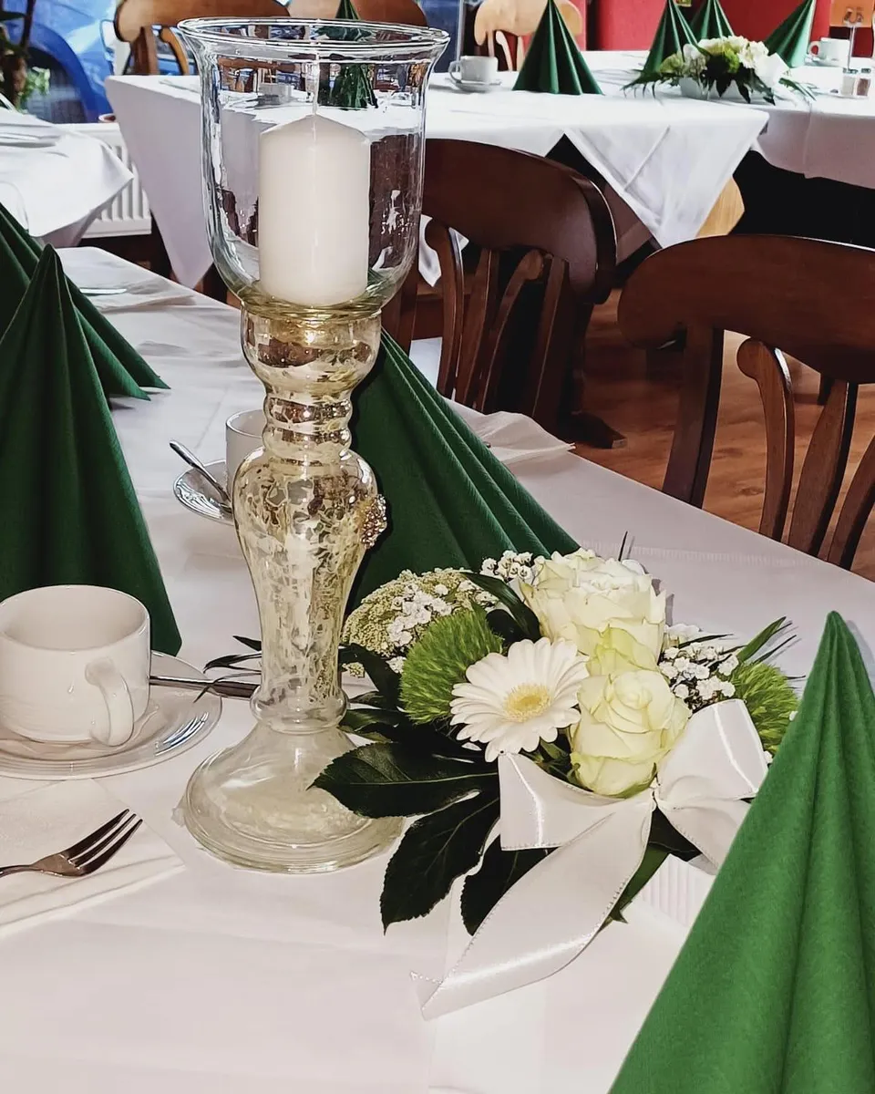 Festliche Tischdekoration mit tannengrünen Servietten, weißen Blumen und Kerzenleuchter
